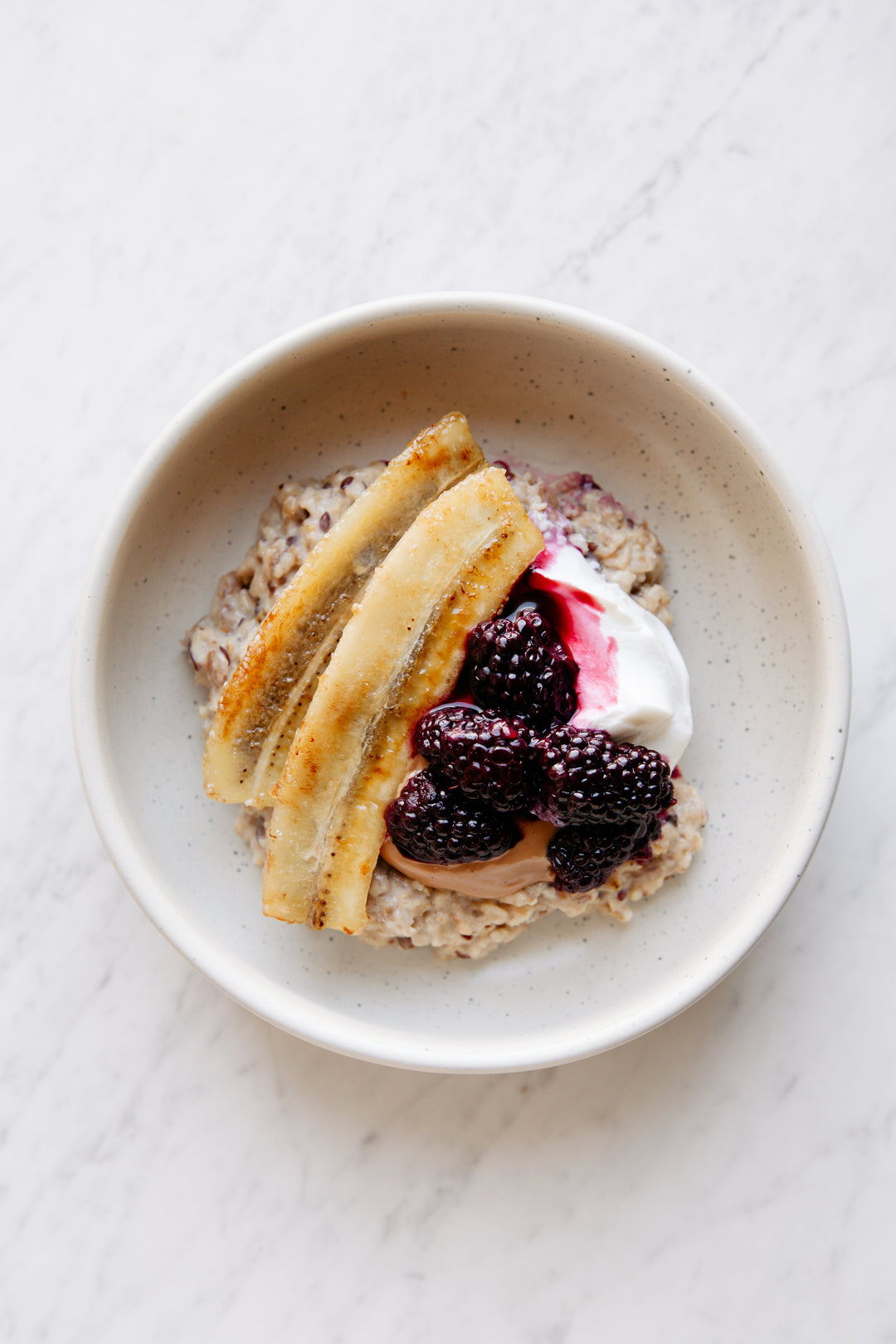 Creamy porridge bowl with caramelized banana, blackberry compote & Greek yoghurt