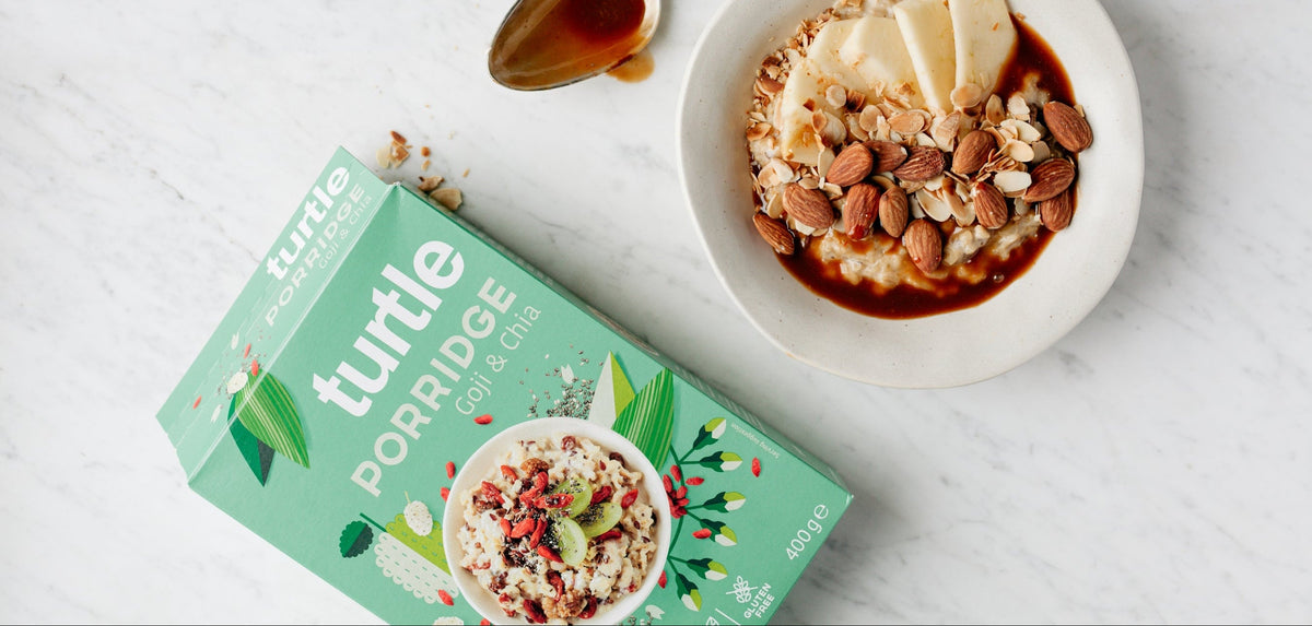Turtle porridge bowl with almonds and a spoon on a white surface